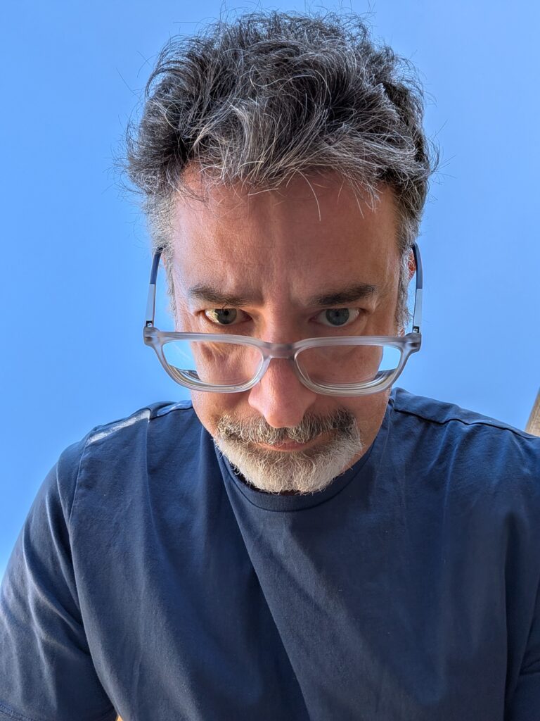 Rod looking down his glasses against a spring blue sky