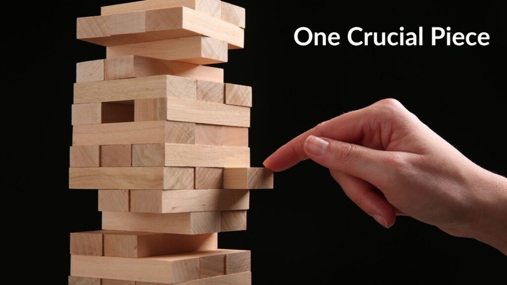 Tentative hand and finger touching one piece in Jenga Tower